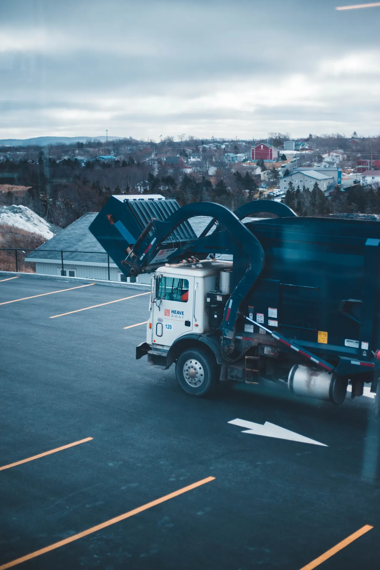 A front-loader refuse truck lifting a waste container